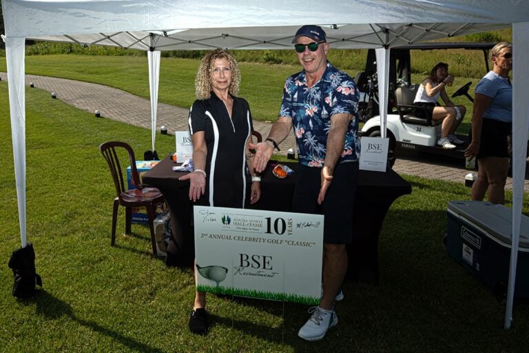 A sponsor from the annual ASHoF golf event shows off their sign